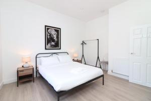 a white bedroom with a bed and two lamps at Hope House Apartments in Chester