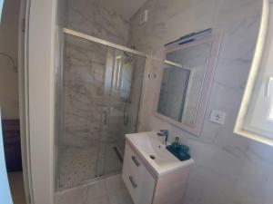 a white bathroom with a shower and a sink at Apartments Tanja in Zavalatica
