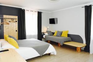 a bedroom with two beds and a couch and a tv at Hotel de la Placette Barcelonnette in Barcelonnette