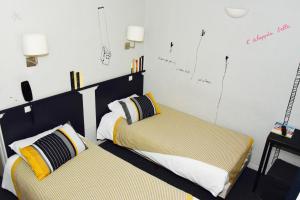 a bedroom with two beds and a desk at Hotel de la Placette Barcelonnette in Barcelonnette