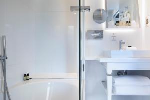 a white bathroom with a tub and a sink at Hôtel Baume in Paris