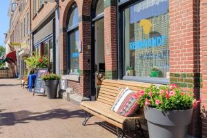 a wooden bench sitting in front of a building with flowers at City Hotel Rembrandt in Leiden