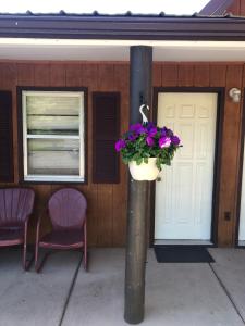 a porch with two chairs and a flower pot on a pole at Spring Creek Inn in Hill City