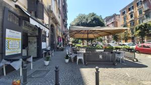 a sidewalk with tables and chairs and an umbrella at Gennaro & Partenope in Naples