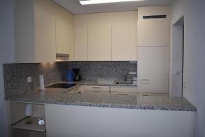 - une cuisine avec des placards blancs et un plan de travail en granit dans l'établissement Astoria (105 Sh), à Lenzerheide