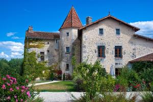 una vieja casa de piedra con flores delante en Chateau de Gurat, en Gurat