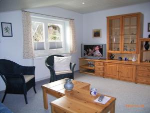 ein Wohnzimmer mit einem TV, 2 Stühlen und einem Tisch in der Unterkunft Pension Alte Bäckerei in Kosel in Kosel