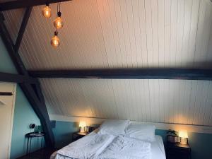 a bed with white sheets and pillows in a room at Logies De Reiziger in Groede