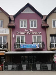 a pink building with a sign on it at Pokoje gościnne LUSIA in Łeba
