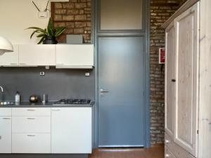 una cocina con armarios blancos y una puerta azul en Besselaar Apartments, en Maastricht