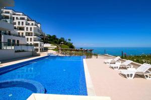 a swimming pool with chairs and the ocean in the background at Бяла Виста Клиф - Byala Vista Cliff in Byala