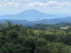 a view of a mountain in the distance with trees at Hoshi no Sato in Kirishima