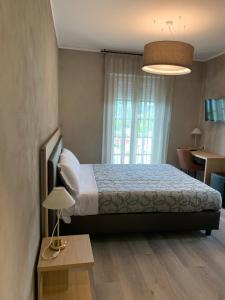 a bedroom with a bed and a table and a window at Hotel Conca D'Oro ***S in Garda