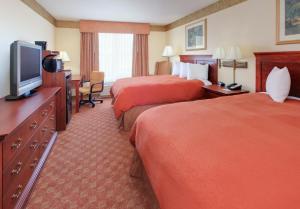 a hotel room with two beds and a flat screen tv at Country Inn & Suites by Radisson, Bentonville South - Rogers, AR in Rogers