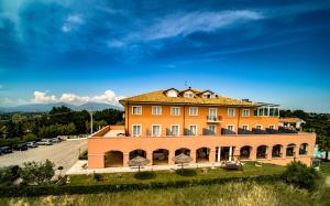 un grand bâtiment orange au sommet d'une colline dans l'établissement Villa Susanna Degli Ulivi - Resort & Spa, à Colonnella