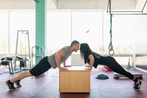a man and woman doing push ups on a box in a gym at Penzion Troja in Lipany