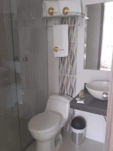 a white bathroom with a toilet and a sink at Hotel Grato Manizales in Manizales
