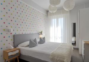 - une chambre dotée d'un lit blanc et d'un mur en point de polka dans l'établissement Hotel Madison, à Rimini