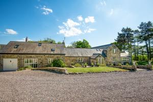 a large stone house with a gravel driveway at Throphill Grange in Morpeth