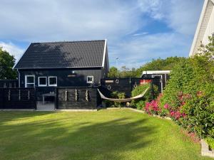 a black house with a hammock in a yard at Skagen anneks in Skagen