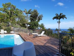 a wooden deck with a swimming pool and the ocean at Domaine Choco Vanille in Deshaies