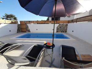 Una sombrilla y sillas junto a una piscina. en Apartman Manuela, en Šibenik