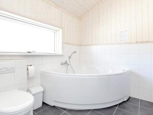 ein weißes Bad mit einer Badewanne und einem WC in der Unterkunft 10 person holiday home in Gro enbrode in Großenbrode