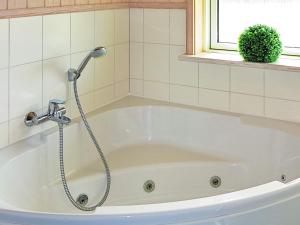 a white bath tub with a shower in a bathroom at 8 person holiday home in Gro enbrode in Großenbrode