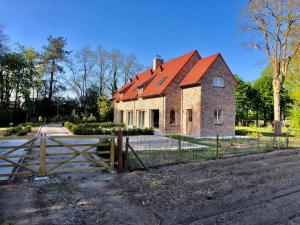 an old brick house with a red roof at Oscaar vakantiewoning in bos in Koekelare