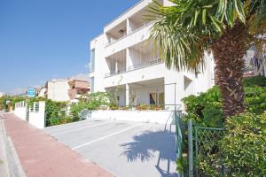 a white building with a palm tree in front of it at Apartmani Srzic in Makarska