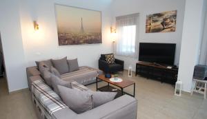 a living room with two couches and a flat screen tv at Eva Villas East, with infinity pool & and panoramic sea view in Gerani