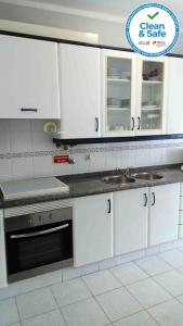 a kitchen with white cabinets and a sink at Sol e Praia - Peniche I in Peniche