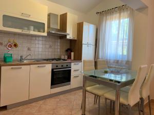 uma cozinha com uma mesa de vidro e uma bancada em Apartments & Room Piutti em Bale
