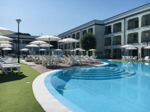 a swimming pool with chairs and umbrellas next to a building at Relaxing Resort Apartment in Lido di Spina