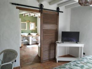 a bedroom with a sliding door with a tv and a bathroom at La résiniere de pirique in Parentis-en-Born