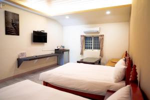 una camera d'albergo con due letti e una televisione di Forest a Manzhou