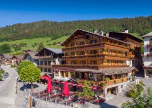 un grand bâtiment avec des parasols rouges dans une ville dans l'établissement Logis La Croix-Saint-Maurice, au Grand-Bornand