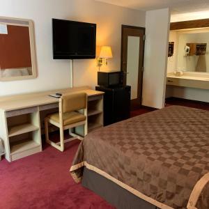 Habitación de hotel con cama, escritorio y TV. en Americas Best Value Inn - Collinsville / St. Louis, en Collinsville
