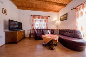 a living room with a brown leather couch and a television at Landhaus am Berg in Rab