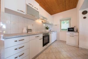 a kitchen with white appliances and a wooden ceiling at Landhaus am Berg in Rab