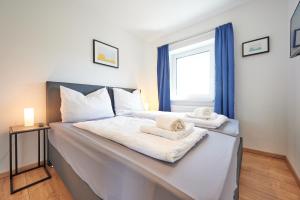 a bed with white sheets and towels on it at Apartments at Winterhafen in Linz