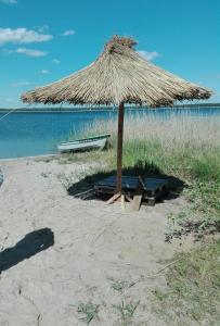 a straw umbrella and a bench on a beach at Domek Letniskowy "Domek Lawendowy" in Pisz