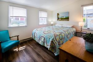 a bedroom with a bed and a blue chair at Truro Beach Cottages in Truro