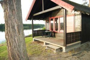 a wooden cabin with a porch next to a tree at Odin Camping AS in Svensrud