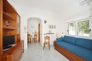 a living room with a blue couch and a kitchen at Appartamenti Villa Maria in Ischia