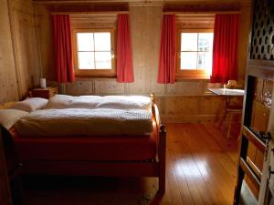 a bedroom with a bed and two windows with red curtains at Chasa Marugg - Ferienwohnung für 4-5 Personen, 70m2 in Scuol