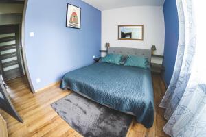 a bedroom with a bed with a blue bedspread at Przestronny Apartament in Grzybowo