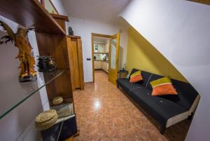 ein Wohnzimmer mit einem schwarzen Sofa und bunten Kissen in der Unterkunft Casa Pueblo Alzira No Compartida in Alzira