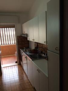 een keuken met witte kasten en een wastafel bij La Residenza in Porto Azzurro