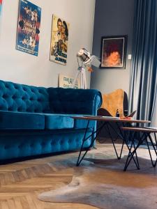 Hostel Sova في نوفي ساد: غرفة معيشة مع أريكة زرقاء وطاولة